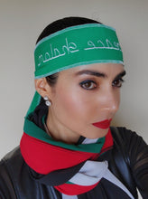 Woman wearing green headband with embroidered text in white reading "Peace, Shalom".